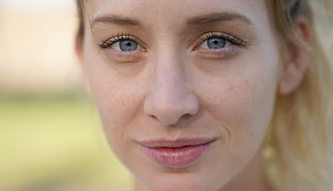 Close-up portrait of a woman with blue eyes and blonde hair looking directly at camera.