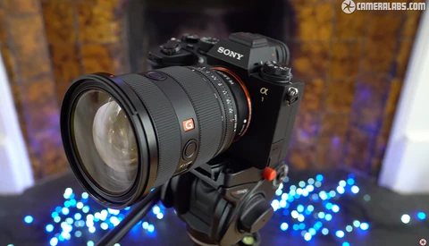 Sony Alpha mirrorless camera with telephoto zoom lens mounted on tripod head, surrounded by blue bokeh lights.