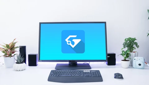 Desktop setup with monitor displaying blue icon app on clean white desk.