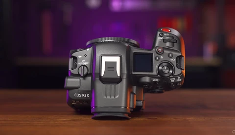 Three Canon EOS mirrorless cameras arranged to show their top and side profiles against a blurred purple and orange background.