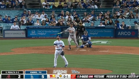Baseball pitcher in white uniform mid-delivery during professional game with crowded stadium stands in background.