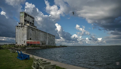Abandoned concrete grain elevator beside Lake Michigan with dramatic cumulus clouds.