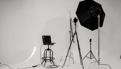 Professional studio lighting setup with softbox, light stands, and reflector on white backdrop.