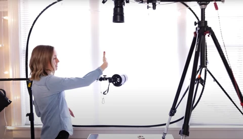 Photographer adjusting a ring light mounted on a tripod during a studio setup.