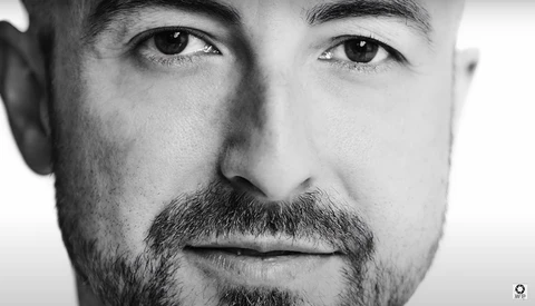 Black and white portrait of a man with dark eyes and full beard looking directly at camera.