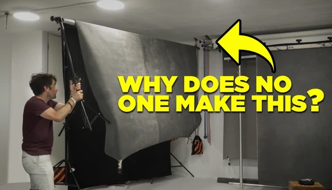 Photographer adjusting a large reflector panel mounted on a C-stand in a studio setting.