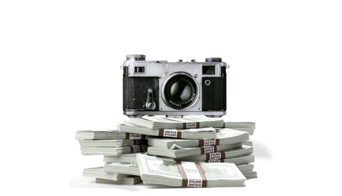 Vintage rangefinder camera positioned atop a stack of bundled currency bills.