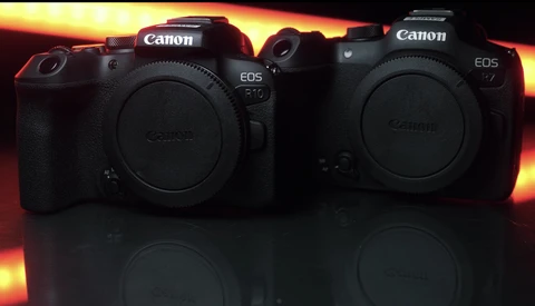 Two Canon EOS mirrorless camera bodies displayed side-by-side against a dramatic golden and orange gradient background.