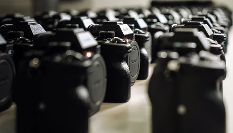 Row of black DSLR camera bodies lined up in selective focus display.