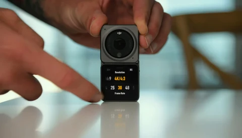 Compact modular camera system with square lens module mounted on rectangular display unit held in hands.
