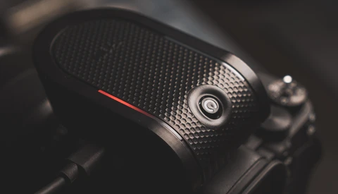 Close-up of a camera handgrip with textured black rubber surface and a red accent line.