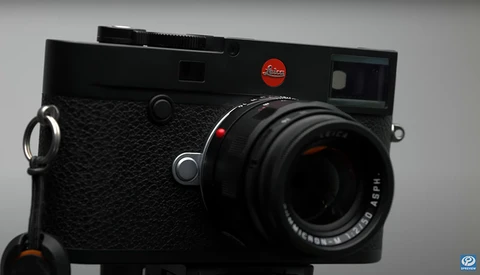 Leica M digital rangefinder camera with black textured body and mounted lens, shown against neutral gray background.