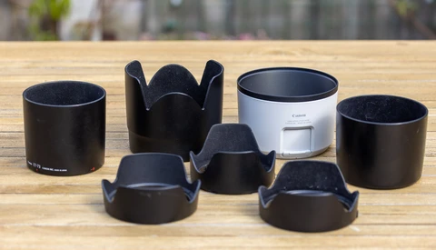 Collection of camera lens hoods in various shapes arranged on a wooden surface.