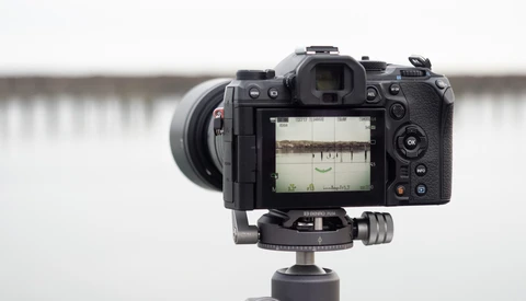 Mirrorless camera mounted on tripod head with electronic viewfinder and wide-angle lens attached.
