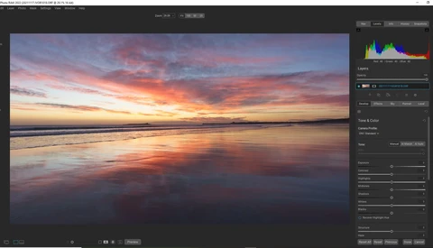 Beach at sunset with golden and pink light reflecting on wet sand and calm ocean water.