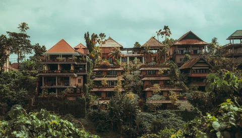 Multi-story wooden buildings with terracotta roofs nestled among dense tropical vegetation.