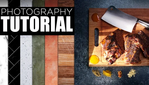 Food photography setup showing cooked meat on a wooden cutting board with a chef's knife, eggs, and spices arranged on a dark textured surface.