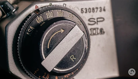 Close-up of a vintage light meter dial with exposure compensation scale and selector needle.
