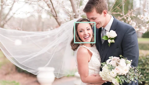 Bride and groom smiling outdoors with bride's face highlighted in a blue square frame overlay.
