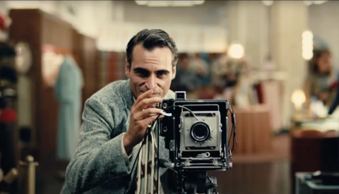 Photographer holding a large format film camera with bellows extended, focused on framing a shot.