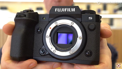 Fujifilm S5 mirrorless camera held in hands, showing open sensor mount with blue sensor visible.