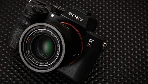 Sony mirrorless camera with attached prime lens on textured dark surface.