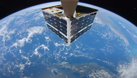 Satellite with solar panels orbiting above Earth's curved horizon with clouds and oceans visible below.