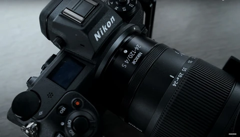 Nikon DSLR camera with attached telephoto lens against a gray background.