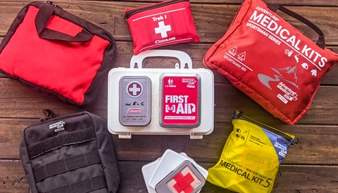 Collection of first aid and medical kits arranged on wooden surface.