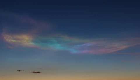 Twilight sky with iridescent cloud displaying rainbow-like colors against deepening blue.