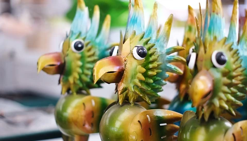 Colorful wooden bird figurines with green, blue, and yellow painted details and carved feather textures.