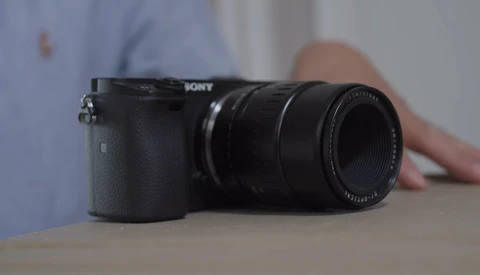 Sony mirrorless camera with attached telephoto lens on a table.