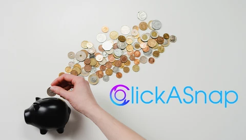 Hand dropping coins into a black piggy bank with coins scattered above on white background.