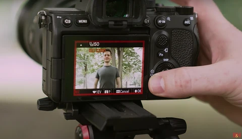 Camera LCD screen displaying a portrait of a man outdoors, with ISO and exposure controls visible.