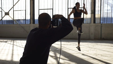 Photographer shooting a runner in motion on a rooftop with industrial architecture and natural window light.