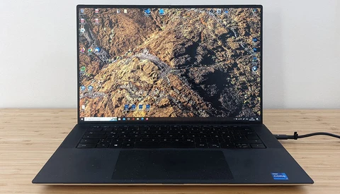 Dark laptop displaying aerial photograph of rocky, mountainous terrain with gold and blue tones.