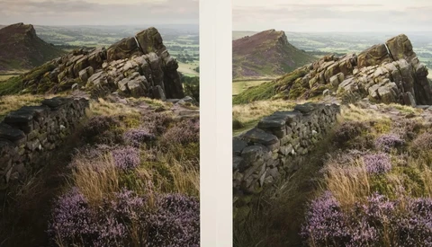 Rocky hilltop with purple heather and stone wall overlooking expansive valley landscape.