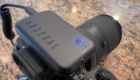 Handheld camera with microphone attachment mounted on textured stone surface.