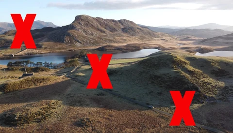 Aerial landscape showing volcanic terrain, multiple lakes, and mountains with three red X marks overlaid on the scene.