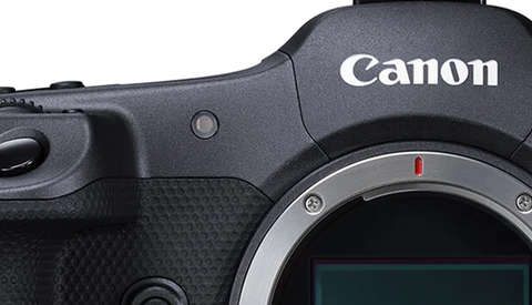 Close-up of Canon camera body showing grip, shutter button, and lens mount with red dot alignment marker.
