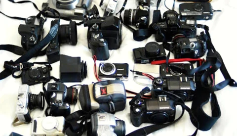 Flat lay collection of vintage film cameras and photography equipment arranged on white background.