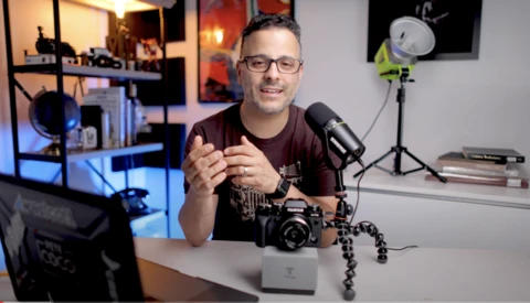 Content creator speaking into a microphone at a desk in a home studio setup.