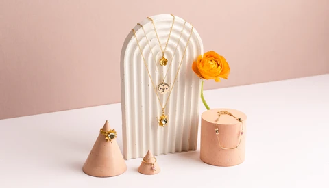 Minimalist still life with arched white sculptural form, peach ceramic vessels, and yellow flower against pink and white background.