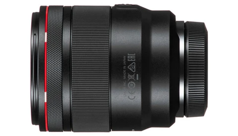 Black camera lens with red accent ring and visible optical elements viewed from the side.