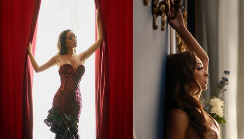 Woman in burgundy sequined dress opening red velvet curtains beside a mirror reflection.