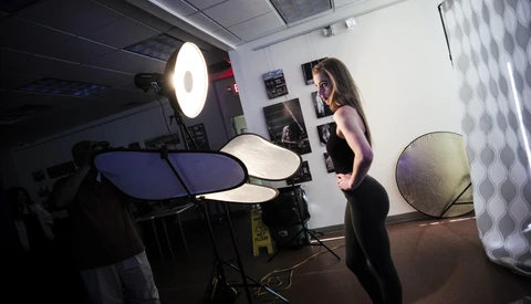 Photographer working with electronic drum pads and studio lighting equipment in a controlled indoor studio setup.