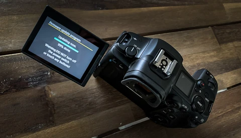 Professional digital camera with articulating LCD screen displaying menu options on wooden surface.