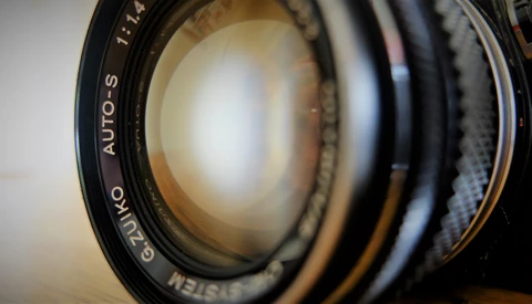 Close-up of a vintage lens showing glass elements and aperture blades with maker markings visible.