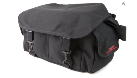 Black canvas camera bag with flap closure and side pockets against a white background.
