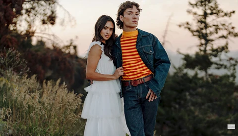 Young couple posing together outdoors at golden hour, with trees in soft focus behind them.
